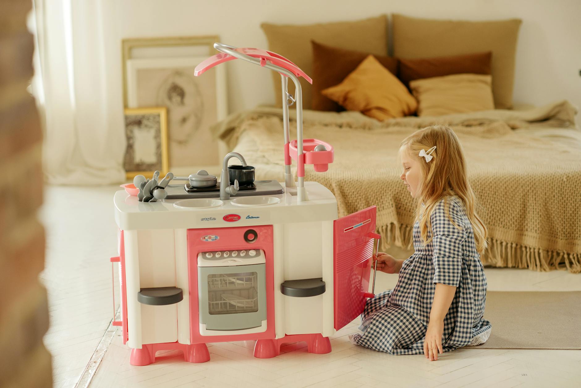 photo of girl in plaid dress playing with kitchen toy